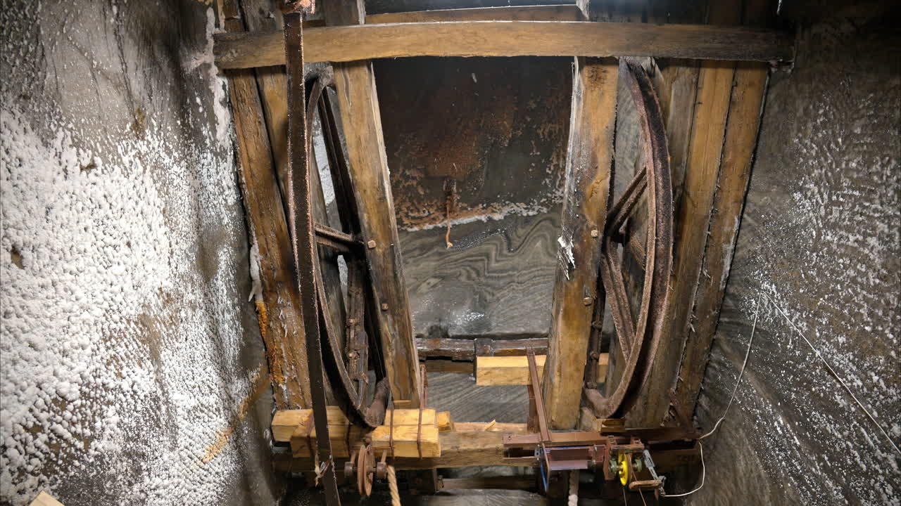 A historic wooden lift system and rusty machinery inside of the Turda Salt Mine in Romania