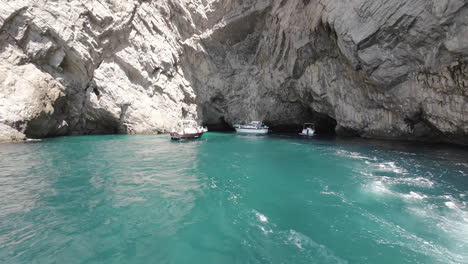 Daytime,-tilt-down-rocky-exterior-to-grotto-and-boats-on-island-of-Capri