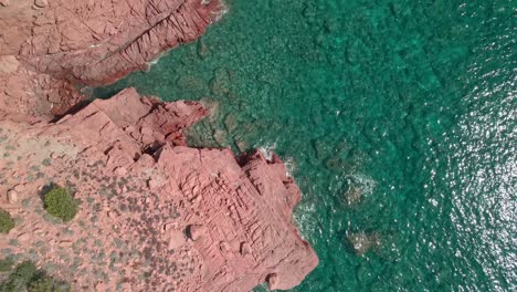 beautiful waves and red rock cliff of sardinia, italy on a sunny day -top view