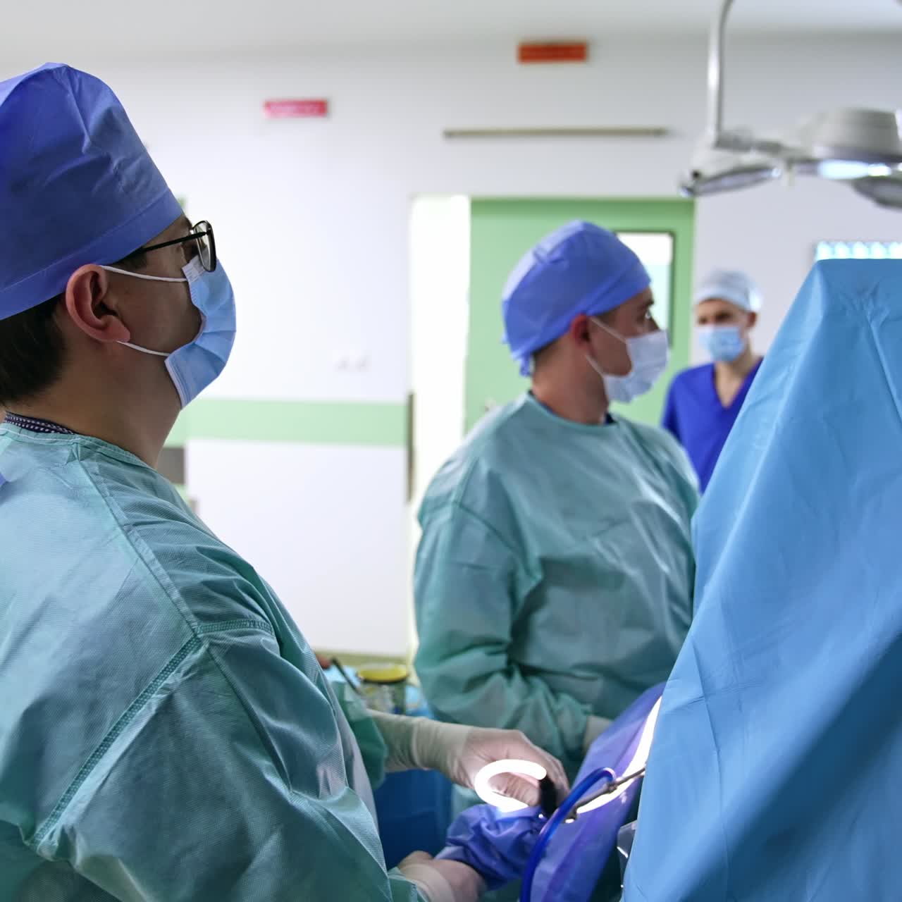 Group of male doctors performing surgery in modern clinics. Medics look at the monitor showing the inner organs of patient