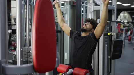 young man exercising on lateral pull at gym - concept of bodybuilding, healthy routine