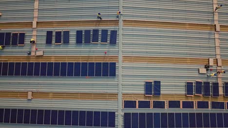 Vista-Aérea-De-Arriba-Hacia-Abajo-De-Muchos-Trabajadores-Industriales-Que-Instalan-Paneles-Solares-En-El-Techo-Para-Energía-Renovable