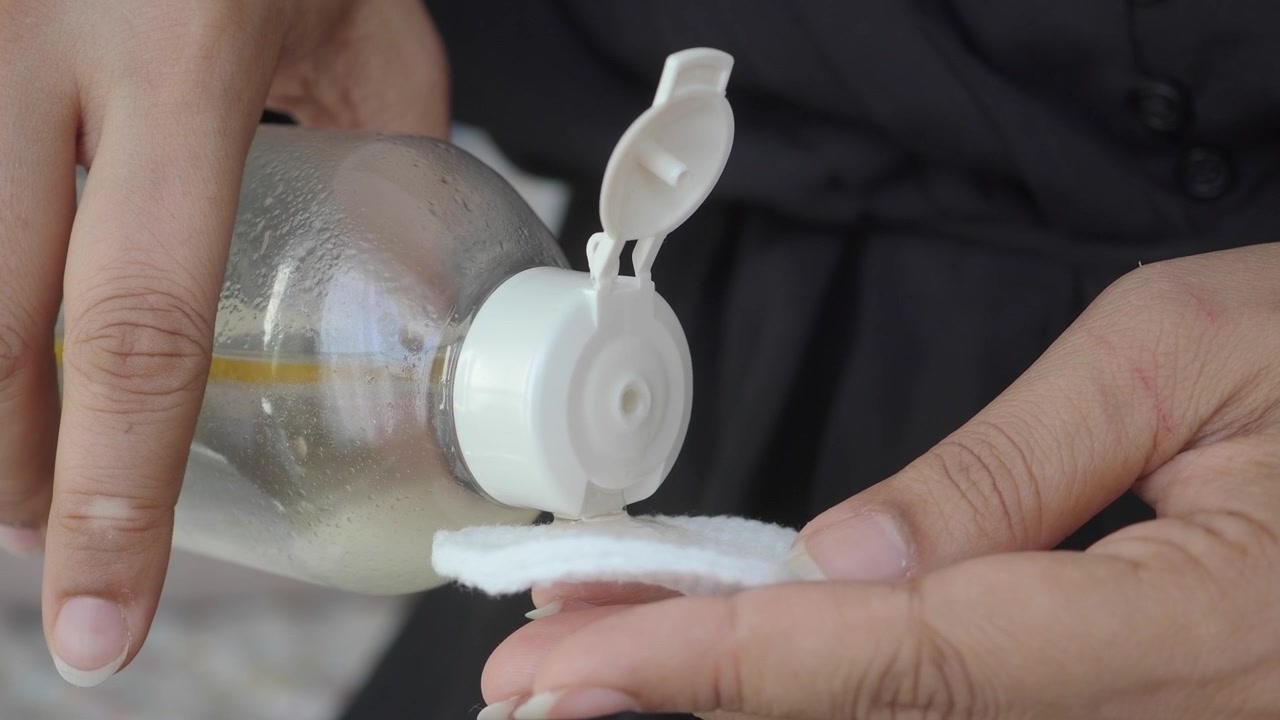 Person Pouring Micellar Water onto a Cotton Pad
