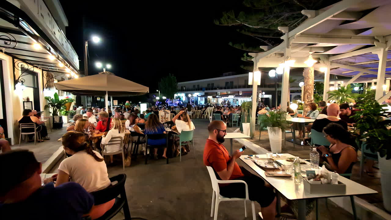 Gimbal shot of the food neighborhood esplanade in Agios Nikolaos with people sitting and eating, slow motion