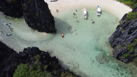 tourists enjoy exotic hidden beach between karsts and jungle, el nido