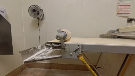 raw dough rolling up onto a pin on a machine.