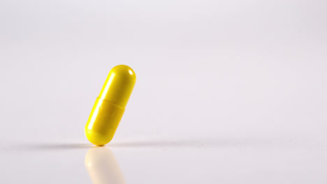 one yellow medication falling against white background