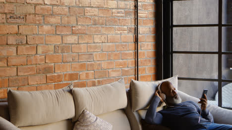 Senior-man-listening-music-on-mobile-phone-in-living-room-4k