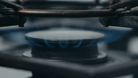 Blue-gas-flame-heating-a-worn-out-pot-on-a-stove