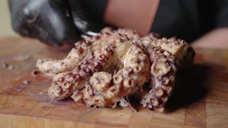 slow motion handheld shot capturing a male chef placing down a boiled octopus on wooden chopping board with steel tong