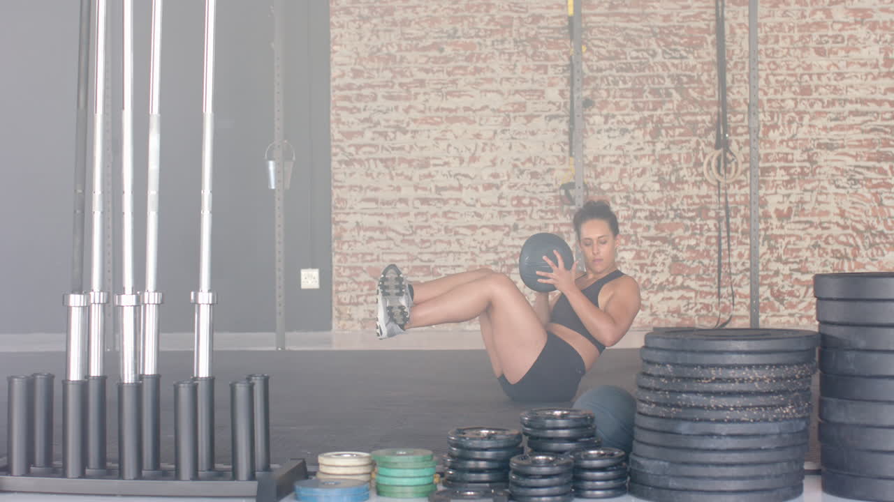 Exercising with medicine ball, strong fit woman performing core workout in gym