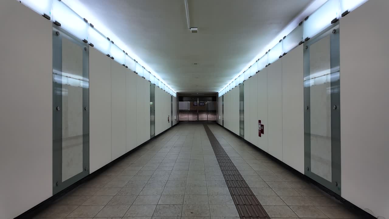 Symmetrical view of an empty, brightly lit underground passageway with clean surfaces. POV, push forward