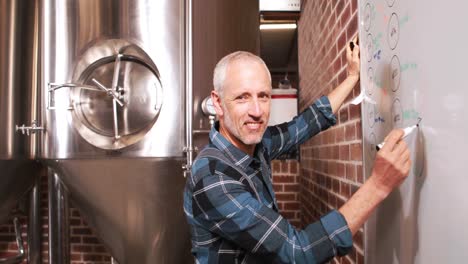 Smiling-brewery-worker-writing-notes-on-whiteboard