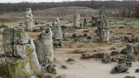 solitary woman walks slowly among ancient rnagnificent natural rock formations