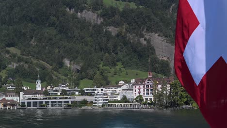 red swiss flag waving off of the back of a ferry on lake lucerne, switzerland