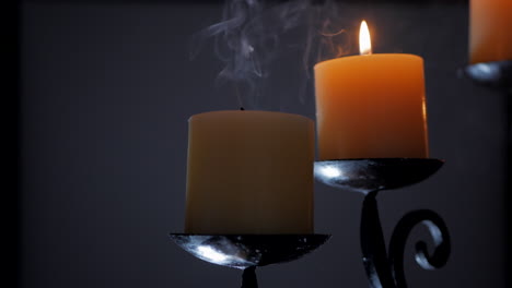 man blowing out a single candle on an ornamental candelabra