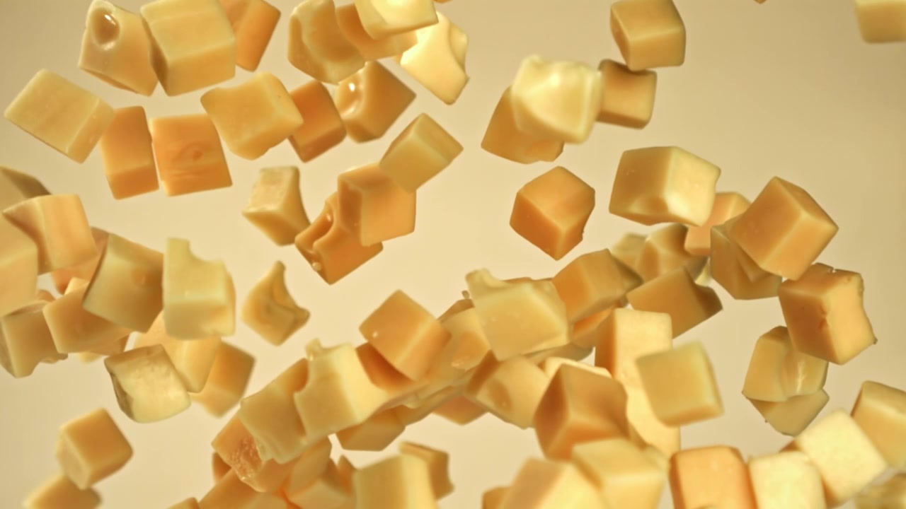 Cubetti di formaggio che cadono al rallentatore su sfondo chiaro