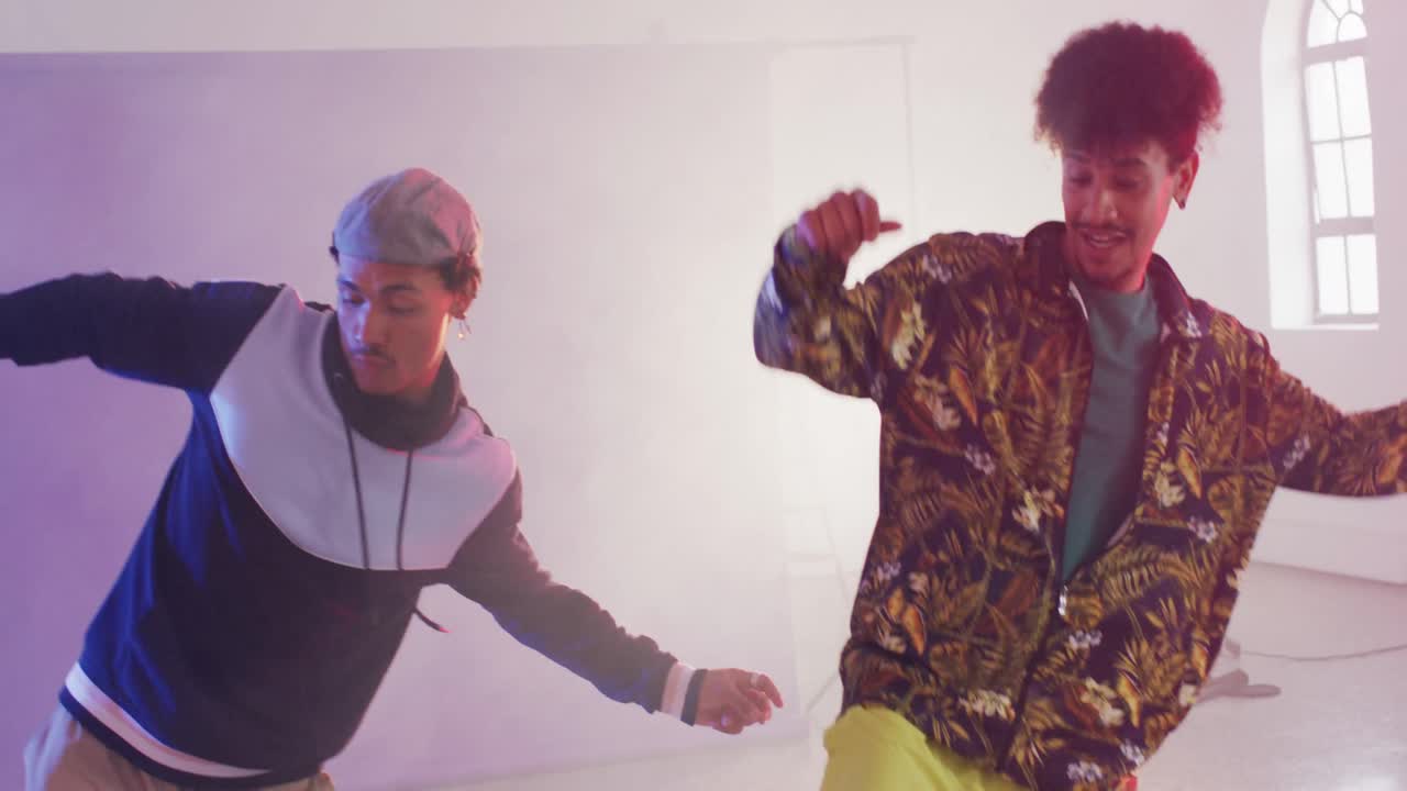 Happy biracial male dancers dancing together in dance studio, slow motion