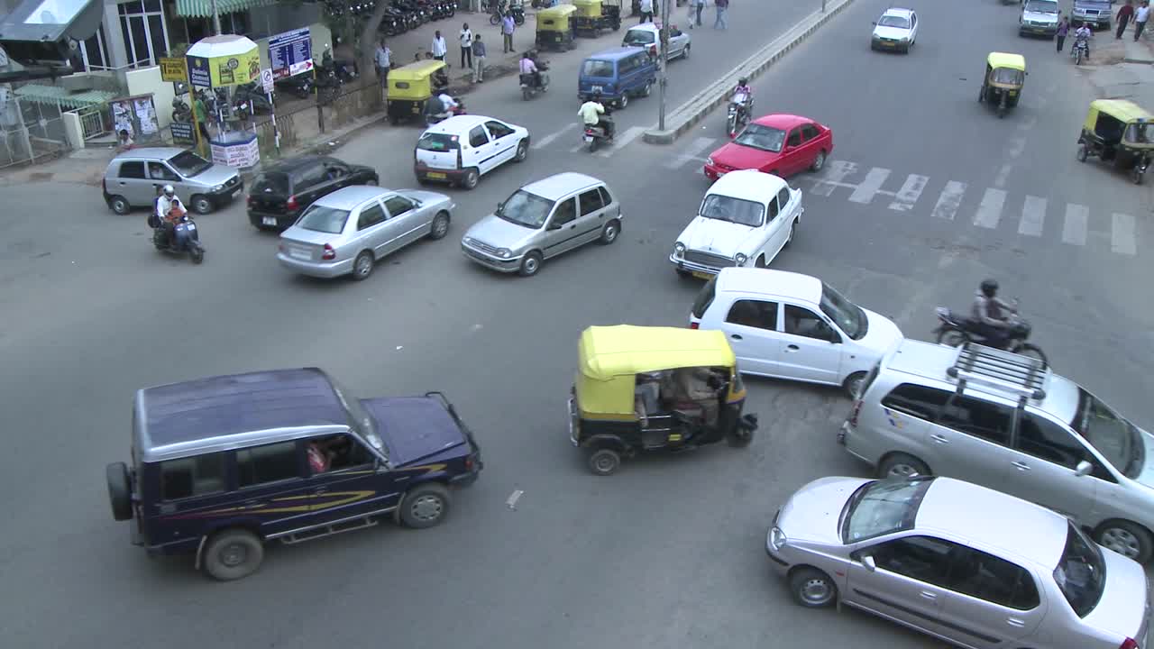 차량과 오토바이는 방향 신호가 없는 혼잡한 교차로를 통과합니다.