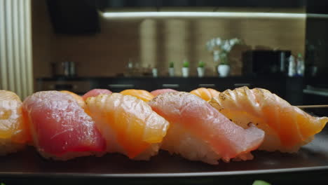 close-up of assorted sushi pieces on a black plate in a kitchen