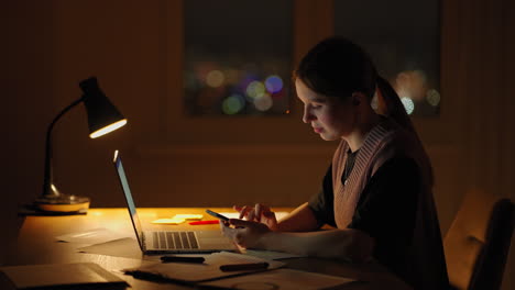 hermosa mujer trabajando hasta tarde en casa usando una computadora portátil y recibiendo mensajes de texto en el teléfono inteligente. manos de mujer enviando mensajes de texto en el teléfono móvil inteligente para la comunicación y el chat en línea social
