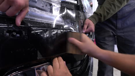 close-up of applying a clear paint protection film to a car bumper