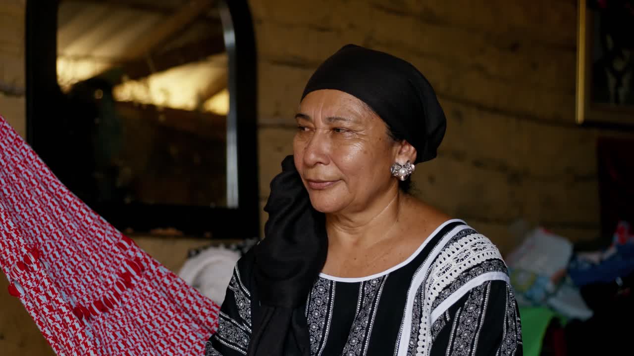 An old Latina woman watches a tube television in her simple home