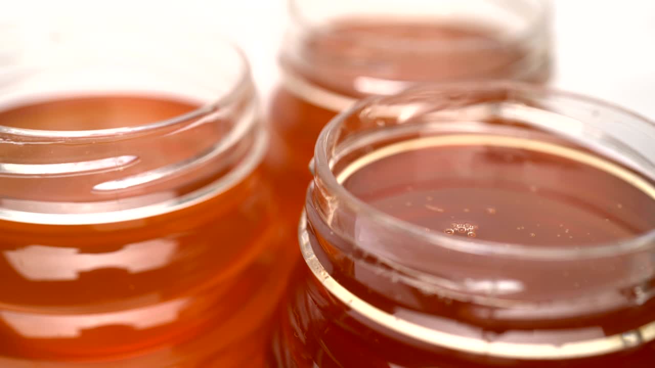Filmato contenitori organici con miele che ruotano su sfondo bianco