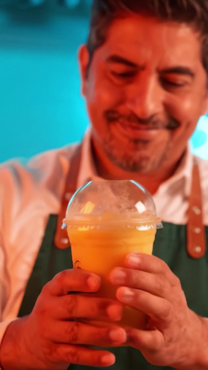 A skilled bartender carefully prepares a vibrant mango smoothie, showcasing the blend of fresh fruits and colorful ingredients in an inviting atmosphere.