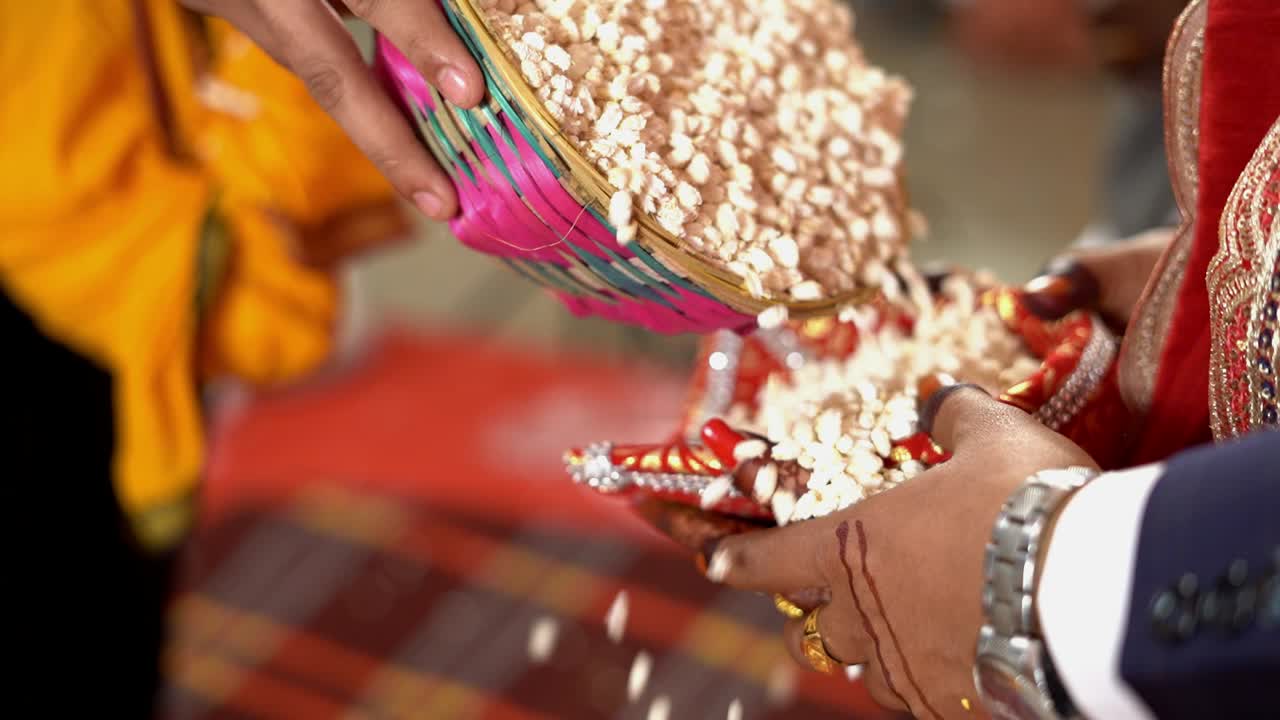 Close up of a couple throwing puffed rice in fire during traditional Hindu wedding. Slow motion shot