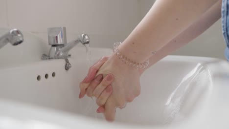 lady washing hands in bathroom sink