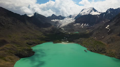 Panning-aerial-drone-shot-of-the-Ala-Kol-lake-with-the-mountain-range-surrounding-it-in-Kyrgyzstan