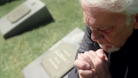elderly man mourns at cemetery