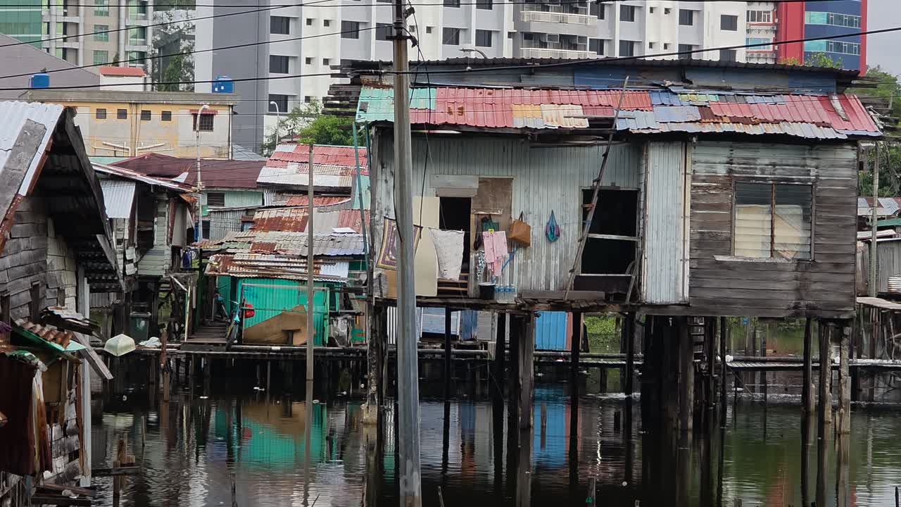 A view of a poor, rustic village built on stilts over the water with traditional wooden houses and shacks in Kota Kinabalu, Sabah, Malaysia - pan reveal