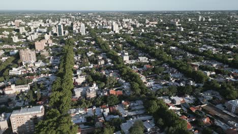 establishing aerial drone shot above mendoza city, argentina, cityscape of urban metropolitan area, buildings, streets, treetops during clear weather