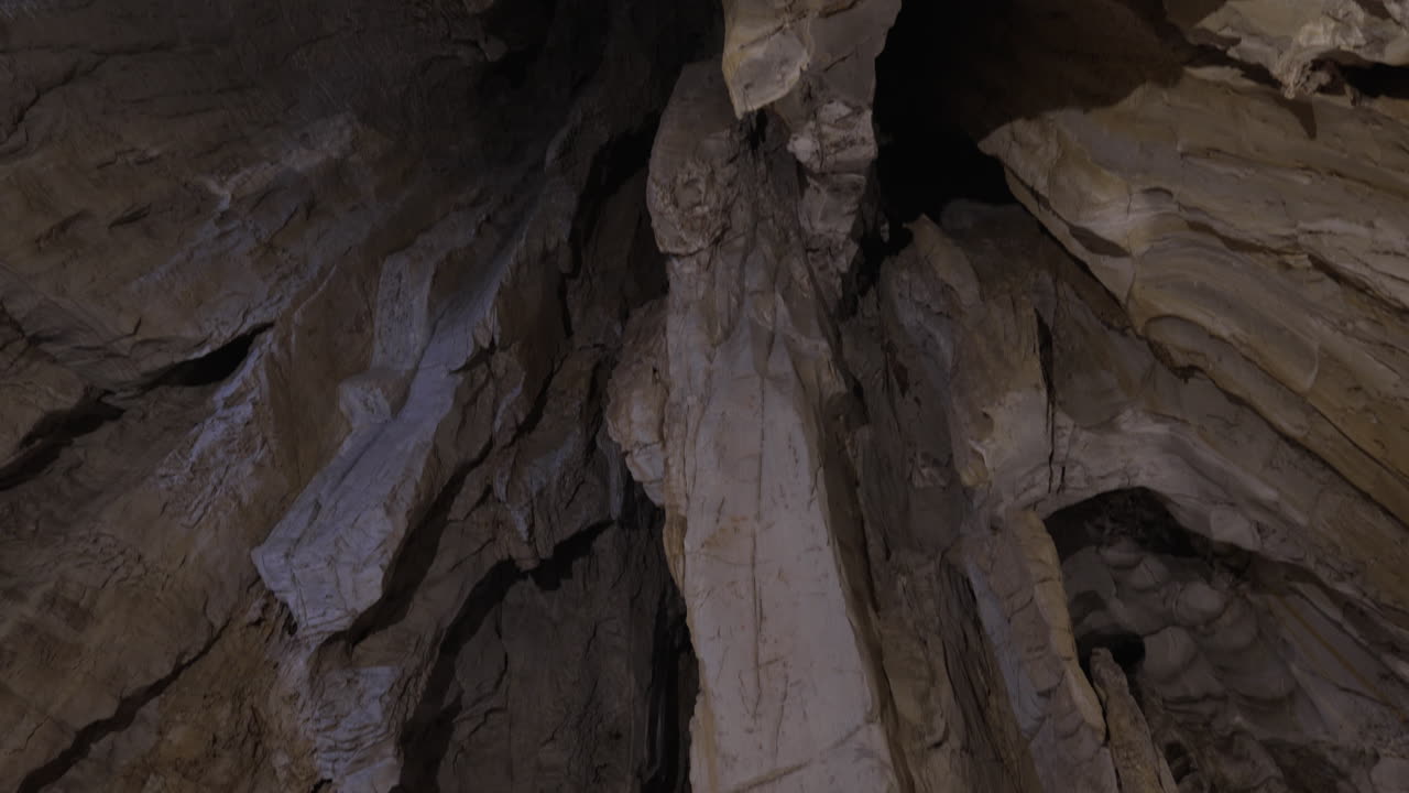 A vast cave interior featuring stalagmites and stalactites, lit dramatically