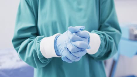 Video-of-midsection-of-surgeon-wearing-surgical-gloves-and-gown-in-operating-theatre