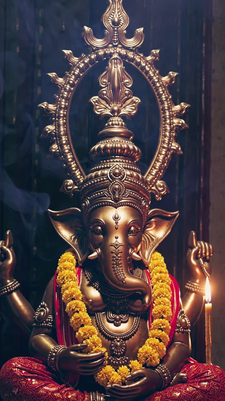 Low-angle shot of a bronze Ganesha statue adorned with marigold garlands, creating a serene