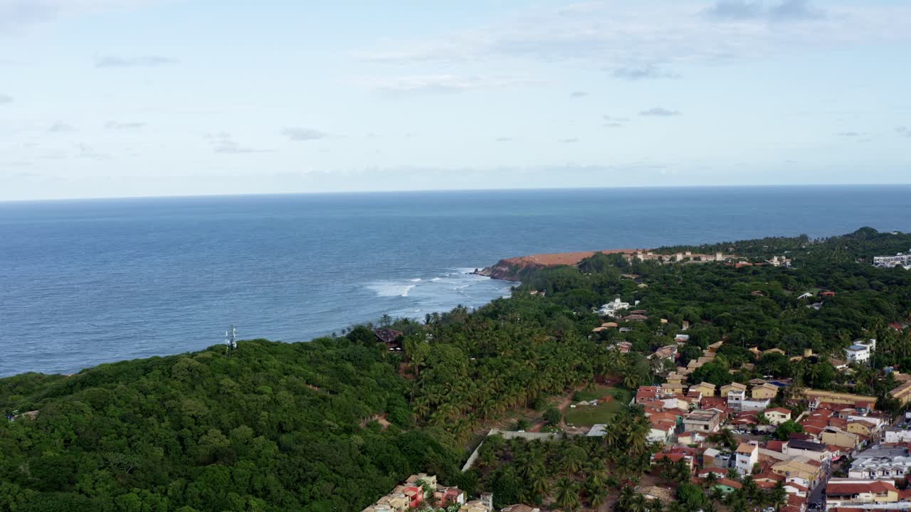 Right trucking wide aerial drone shot of the beautiful tropical Northeastern Brazil coastline and the famous tourist town of Pipa in Rio Grande do Norte covered in exotic green foliage