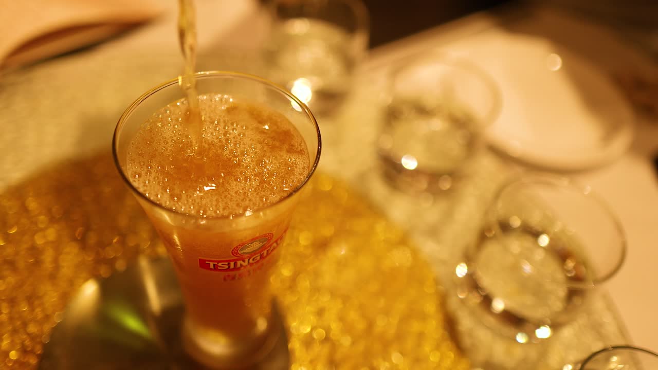 A glass of beer is poured in a warmly lit bar, creating a frothy head. Captured in Gold Coast, Australia