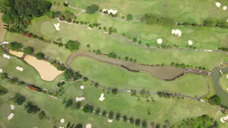 Luftaufnahme-Von-Oben-Mit-Einer-Drohne-Auf-Den-Von-Bäumen-Gesäumten-Golfplatz-Mit-Wasserteich-Als-Wasserhindernis-Und-Sandteich-Als-Bunker