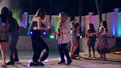 friends dancing at a lively poolside party at night