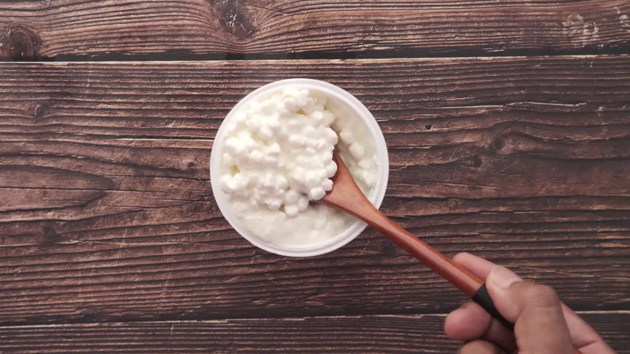 queso cottage en un recipiente blanco con cuchara de madera
