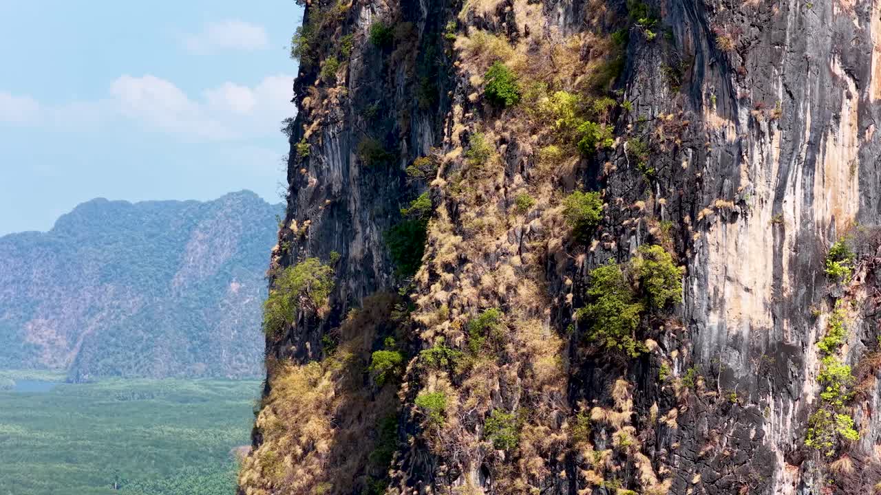 Một chiếc máy bay không người lái quay chậm trên một vách đá vôi gồ ghề nhìn xuống một thung lũng nhiệt đới tươi tốt