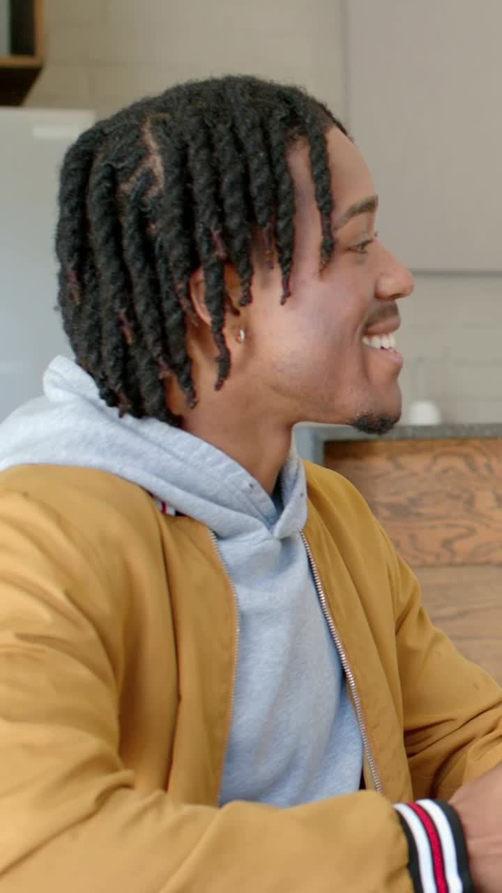 Vertical video: Other hand entering making man in jacket laughing cupping red mug at cafe for chat