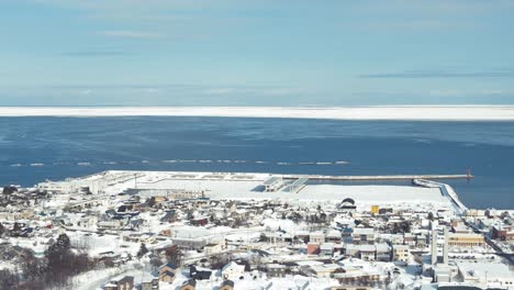 Vista-Aérea-Sobre-La-Ciudad-Invernal-Nevada-De-Omu-Con-El-Mar-De-Okhotsk-En-El-Horizonte-En-Hokaddio