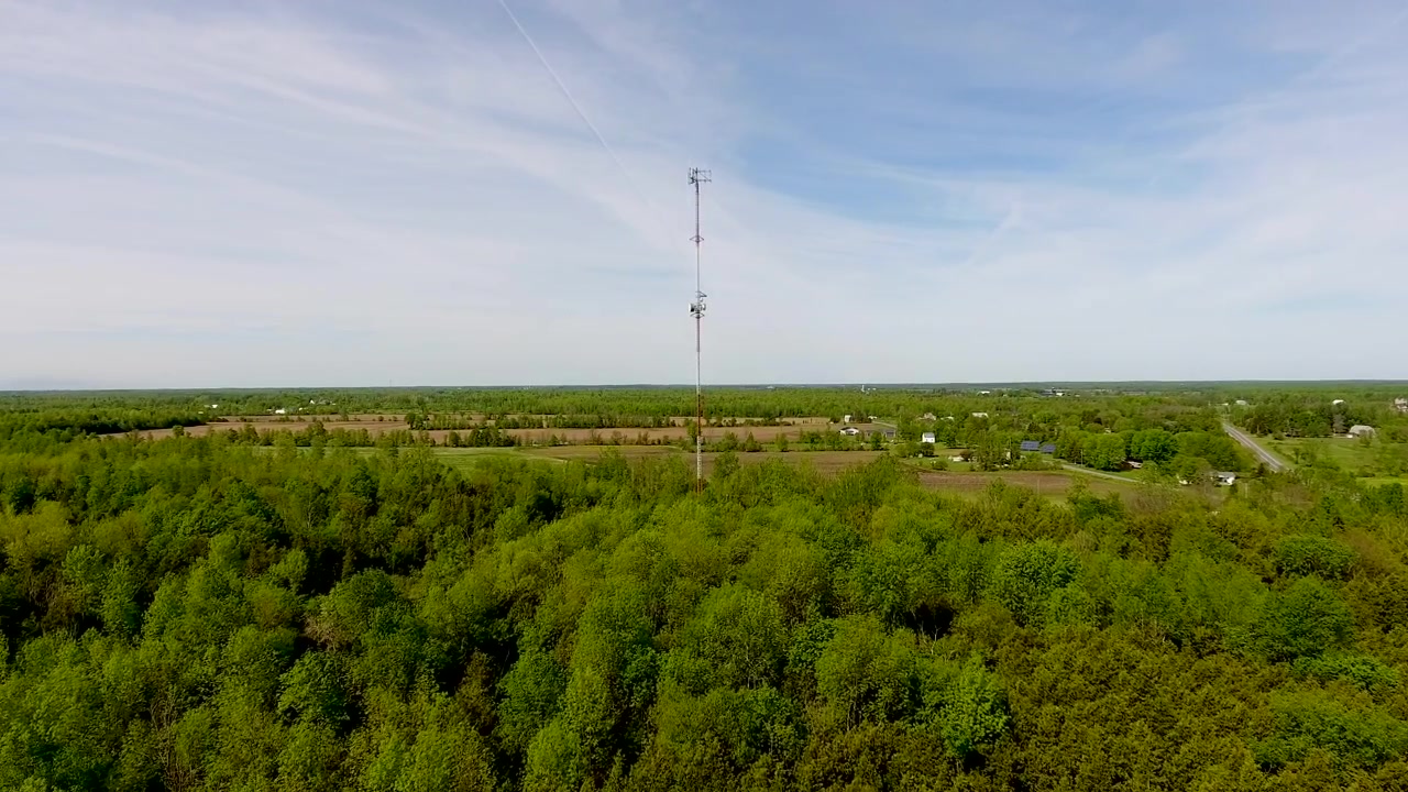 Ripresa aerea in volo verso una torre radio in una zona rurale