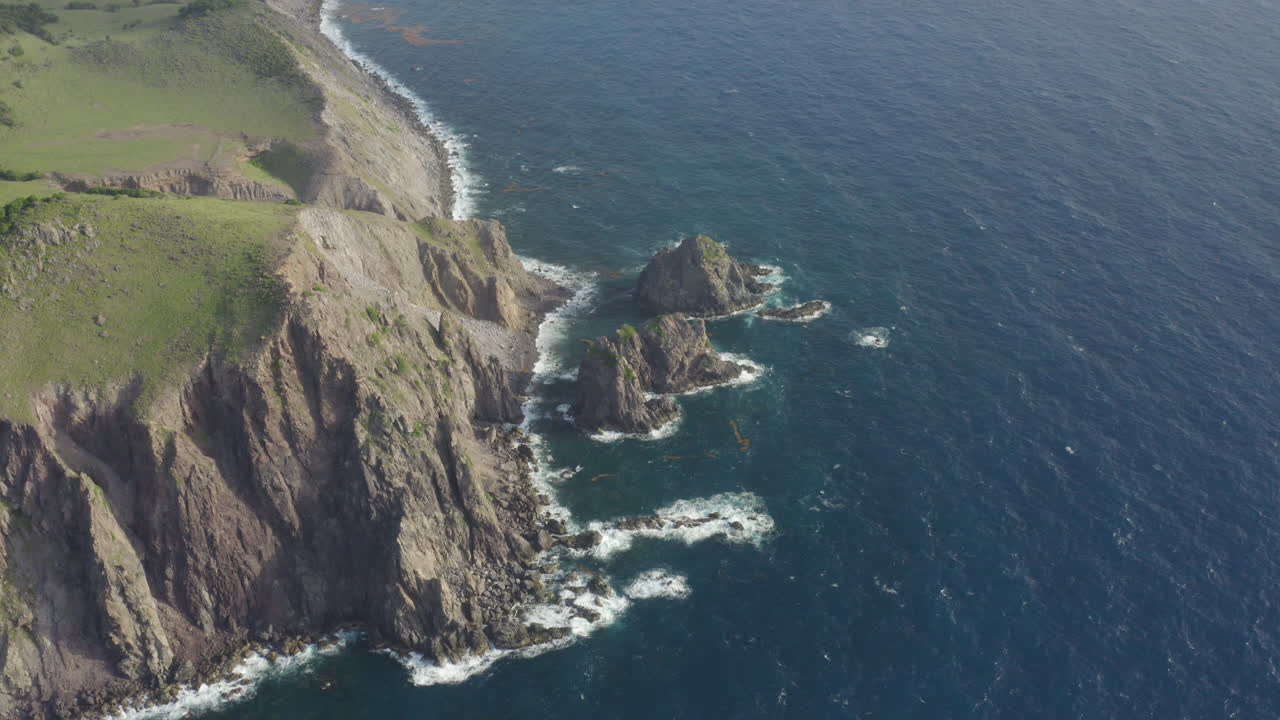 Abandoned Caribbean beach in the early morning. Smooth orbit, high up looking down at cliffs and three large rocks in the ocean. Part 1 of 2.4K UHD at 23.98 fps