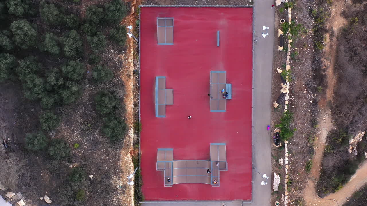 Drone footage Above Small red Skatepark with People Skating
