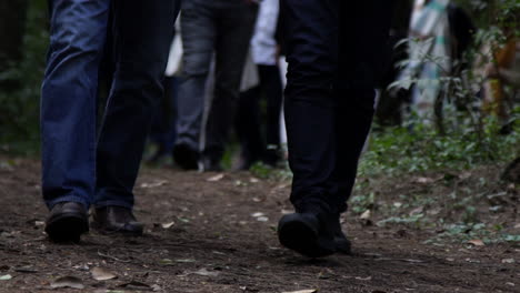 close up of people walking down a dirt road on a cloudy day, legs only